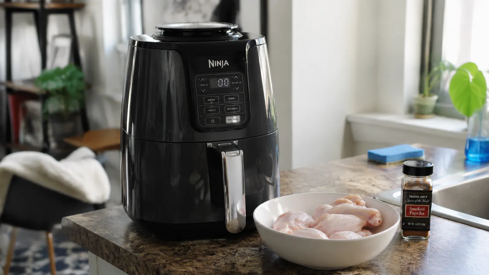 Ninja 4 QT air fryer sitting on a slate-blue kitchen counter next to a small cutting board, warm morning light from a window